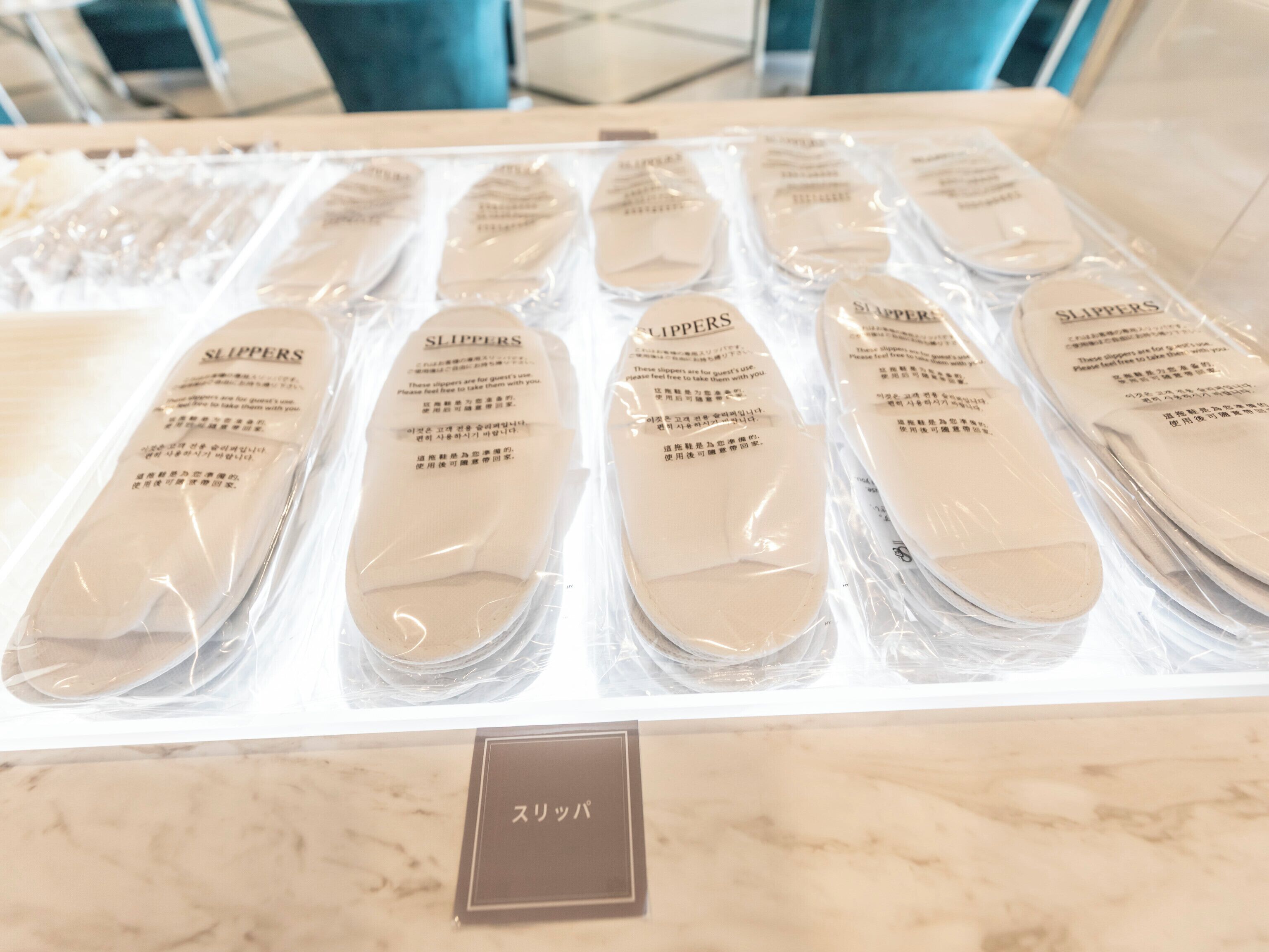 A display of slippers in plastic packaging with labels, arranged on a table.