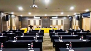 Une salle de conférence avec des rangées de tables, chacune étant équipée de bouteilles d’eau et de verres.