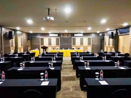 Un salón de conferencias con filas de mesas, cada una con botellas de agua y vasos.