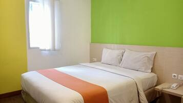 Habitación de hotel con cama, mesita de noche con teléfono y ventana con cortinas.