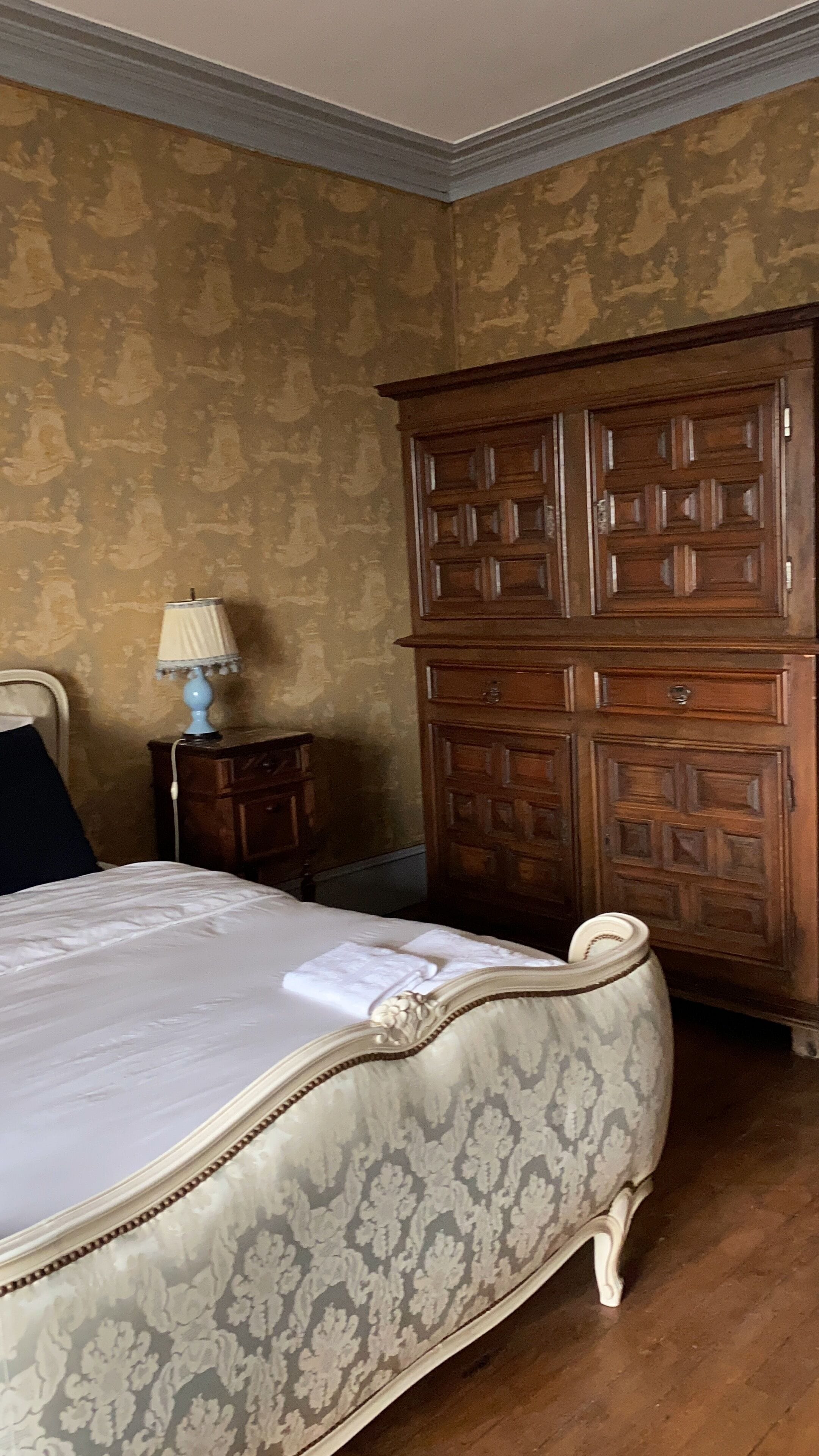 Un dormitorio con una cama, un aparador de madera, una mesita de noche y una lámpara.