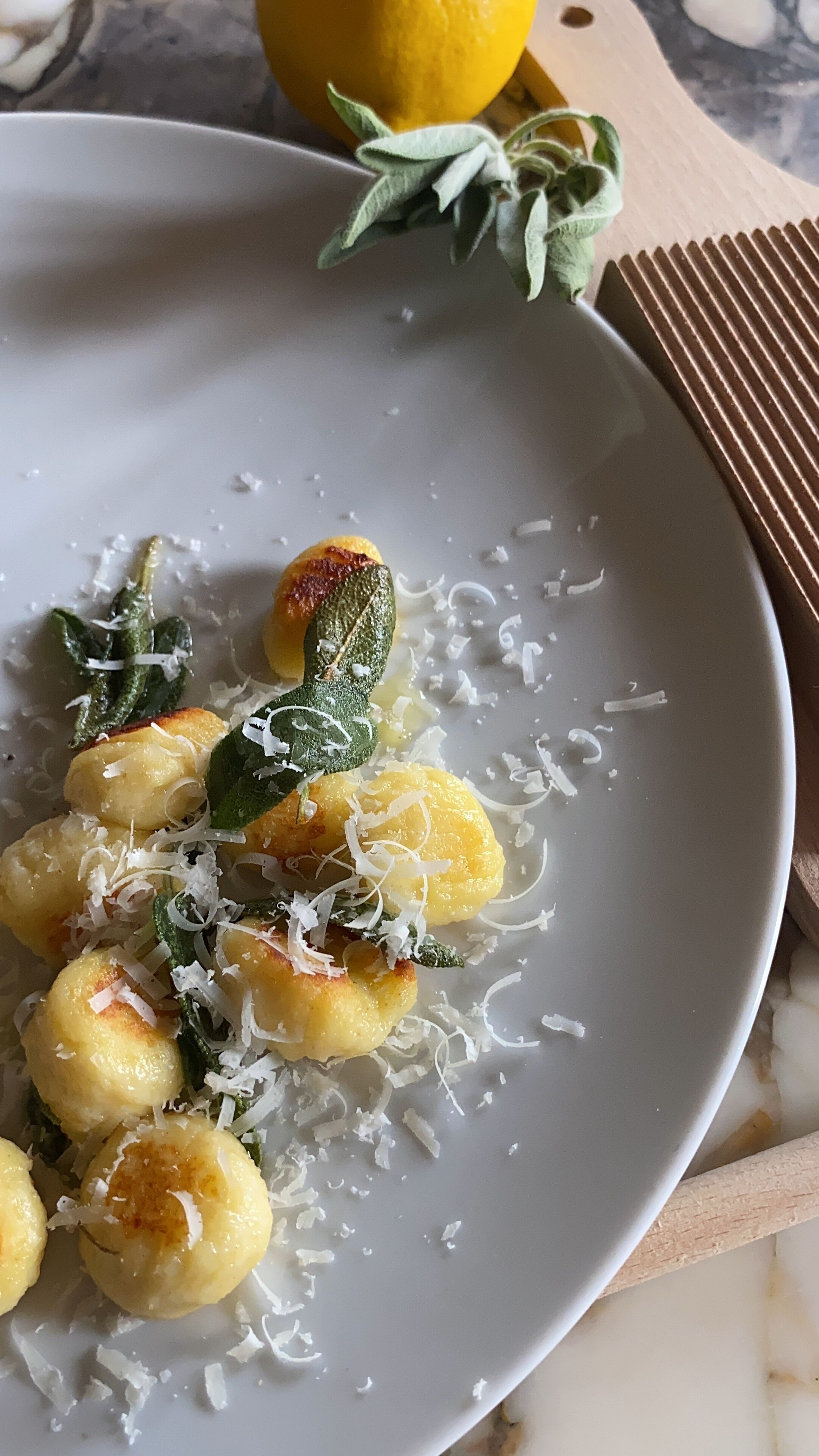 A plate of gnocchi with sage and shaved cheese.