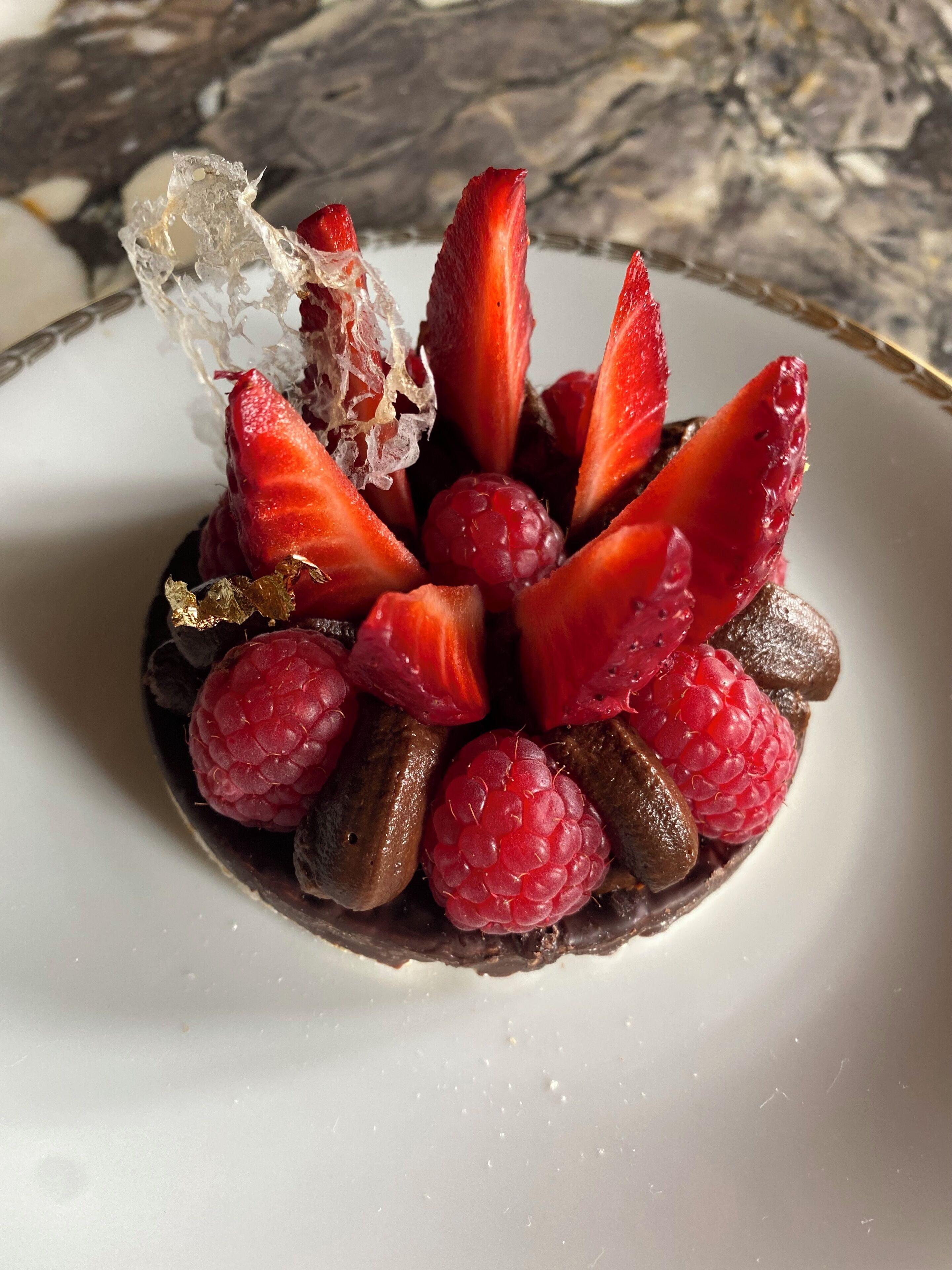 A dessert with strawberries, raspberries, and chocolate pieces on a plate.