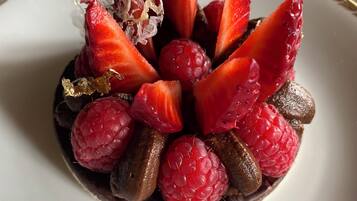 A dessert with strawberries, raspberries, and chocolate pieces on a plate.