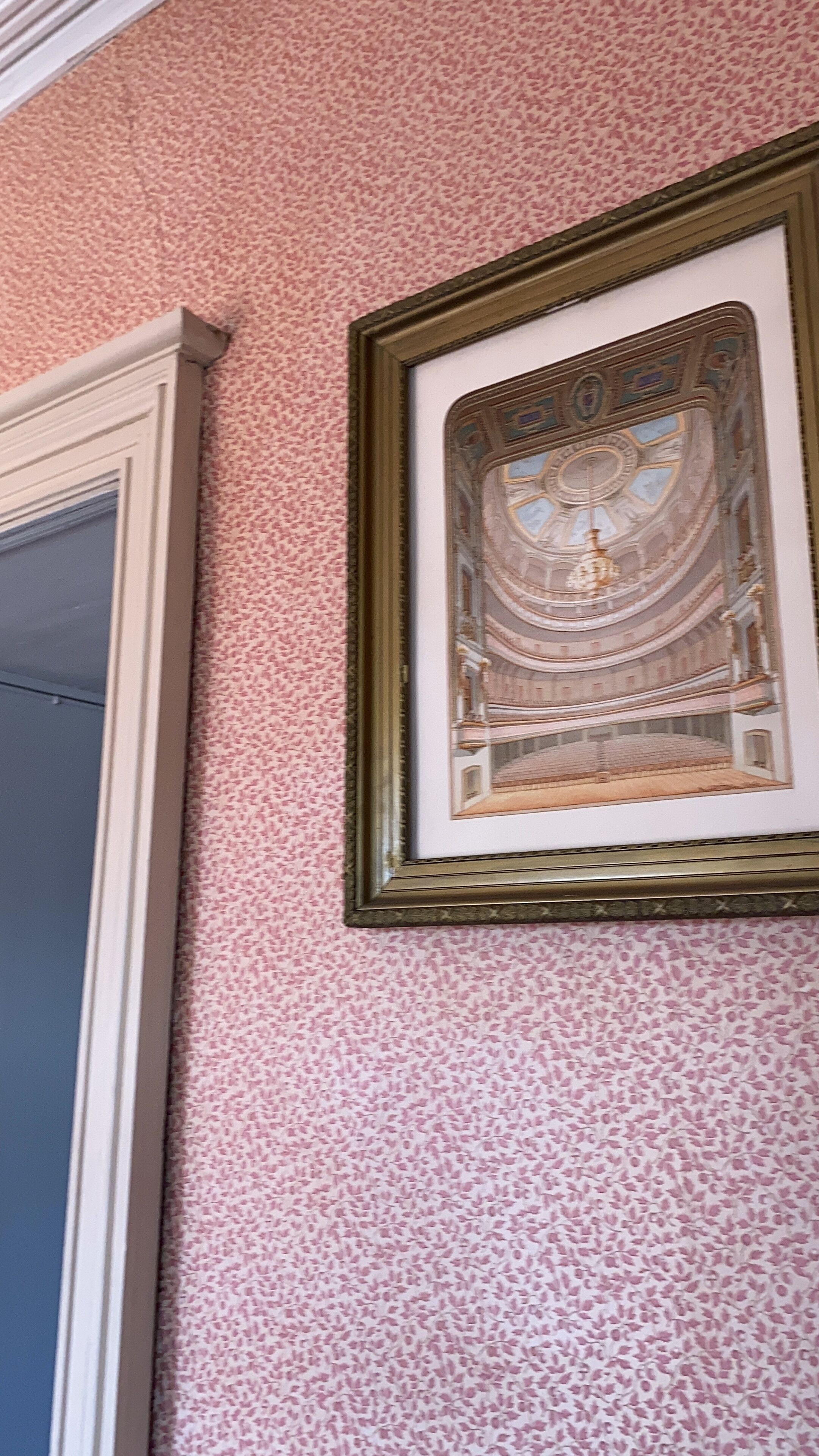A framed architectural drawing on a textured pink wall.