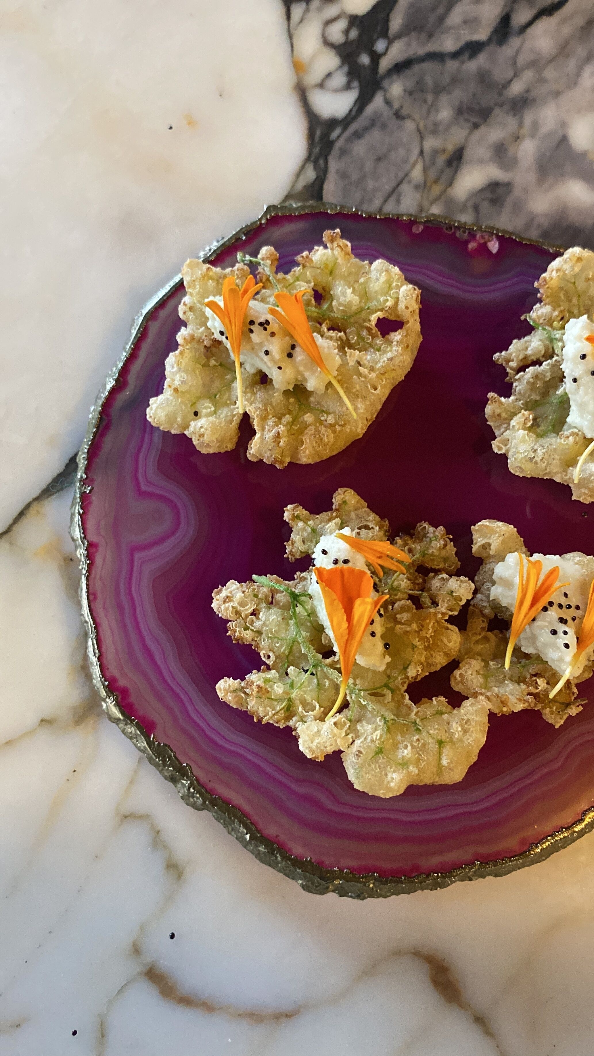 Un plato de aperitivos con un borde decorativo, sobre una superficie de mármol.