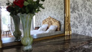 Ein Schlafzimmer mit einem großen Bett, einem Spiegel und einer Vase mit Blumen.