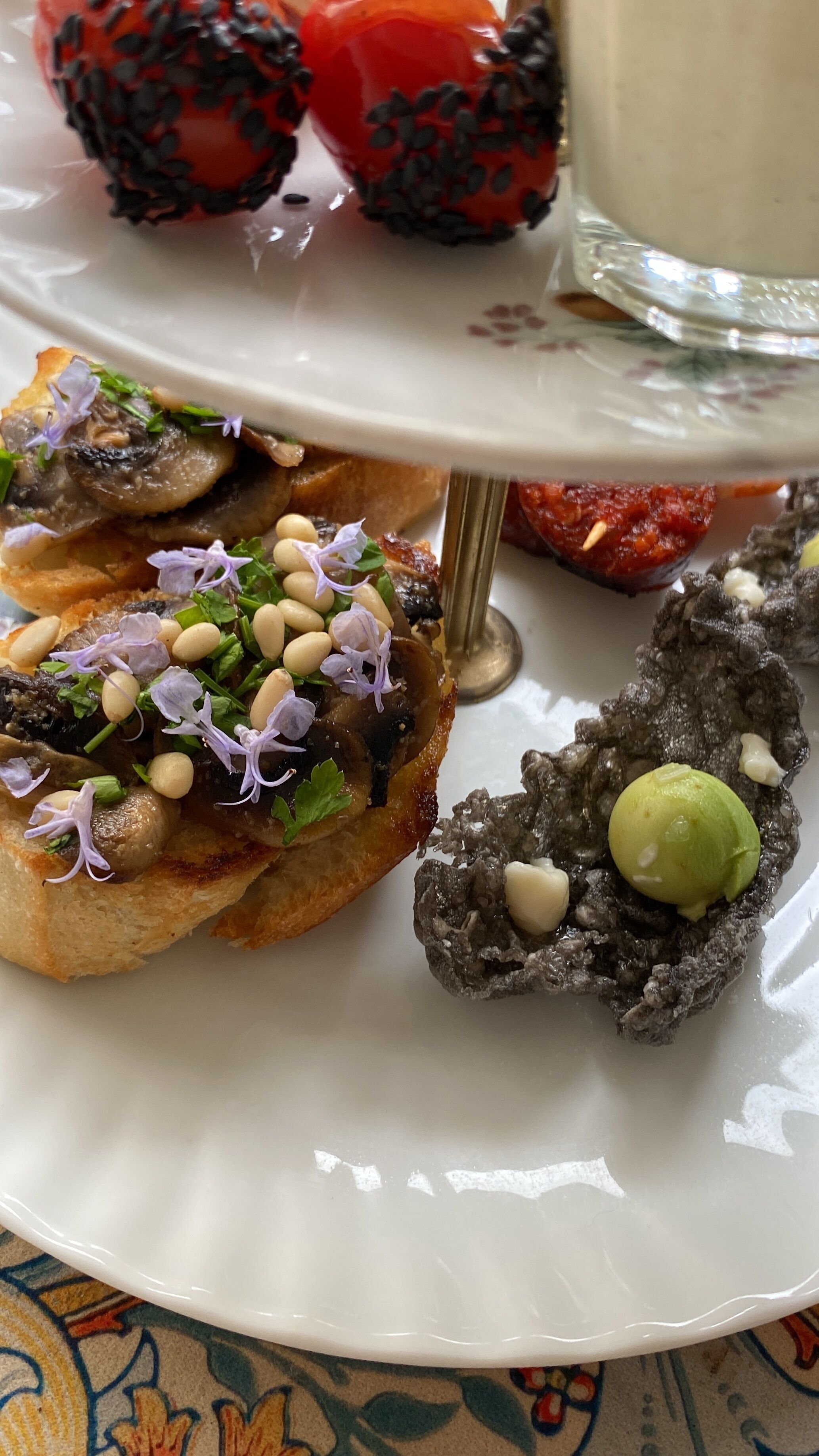 Un plato con diversas entradas, incluyendo un champiñón relleno, una bruschetta con frijoles y hierbas, y un postre con forma de corazón de chocolate.