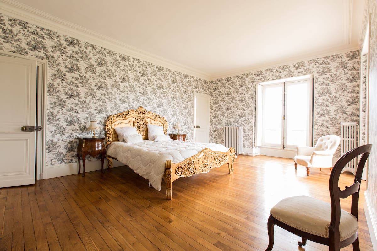 Un dormitorio con una cama grande, una silla y un radiador.