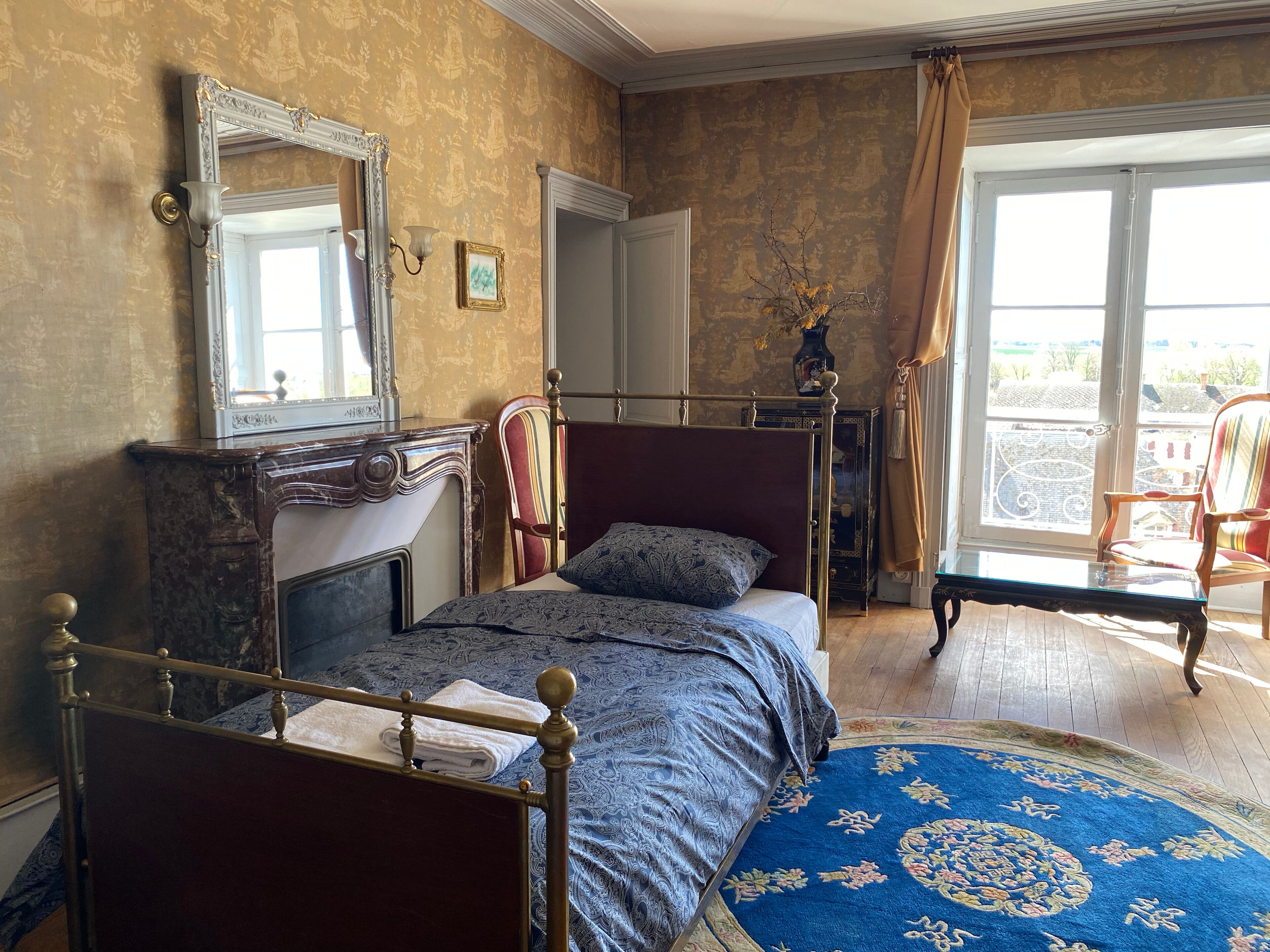 A bedroom with a bed, a dresser, a mirror, a window with curtains, and a view of the outside.
