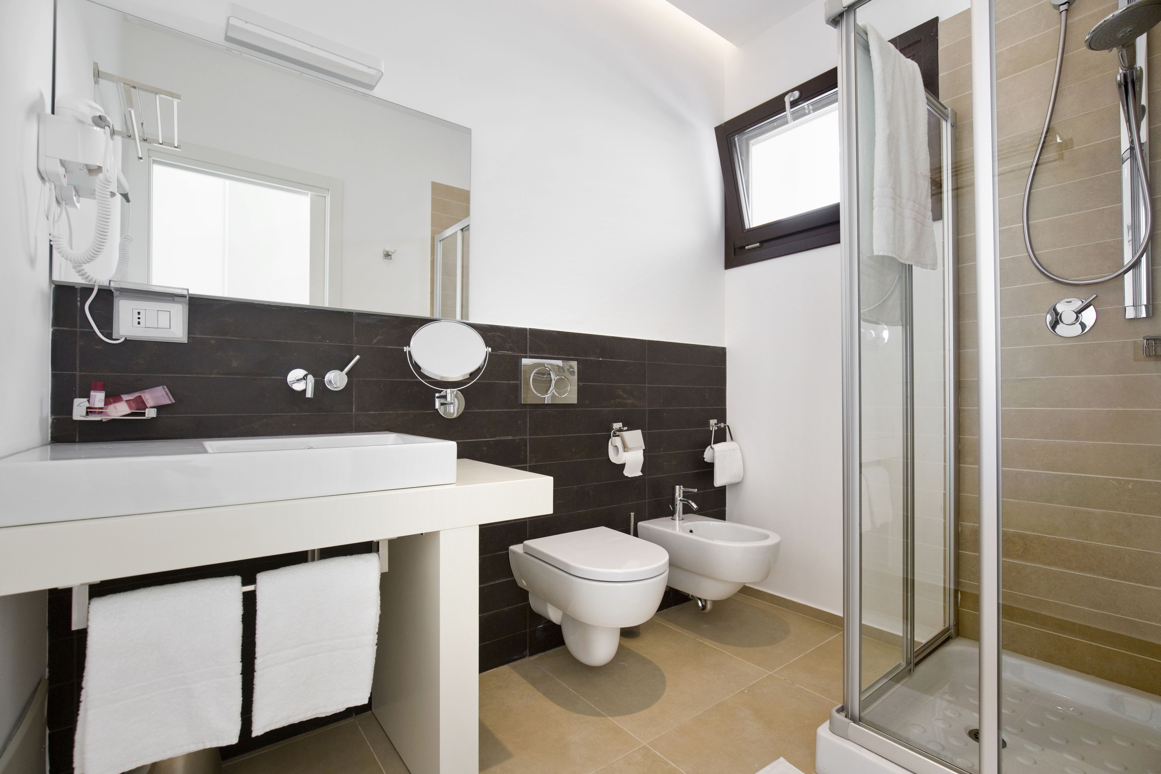 Un baño moderno con ducha, inodoro, bidé y un espejo grande.