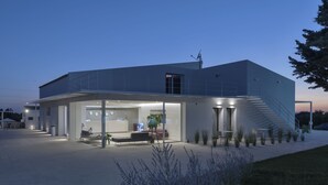 Un edificio moderno con área de recepción, asientos exteriores y una escalera que lleva a la entrada.