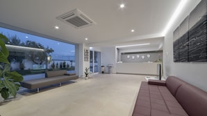 Una sala de estar moderna con un ventanal grande, un sofá, una zona de comedor y una cocina visible al fondo.