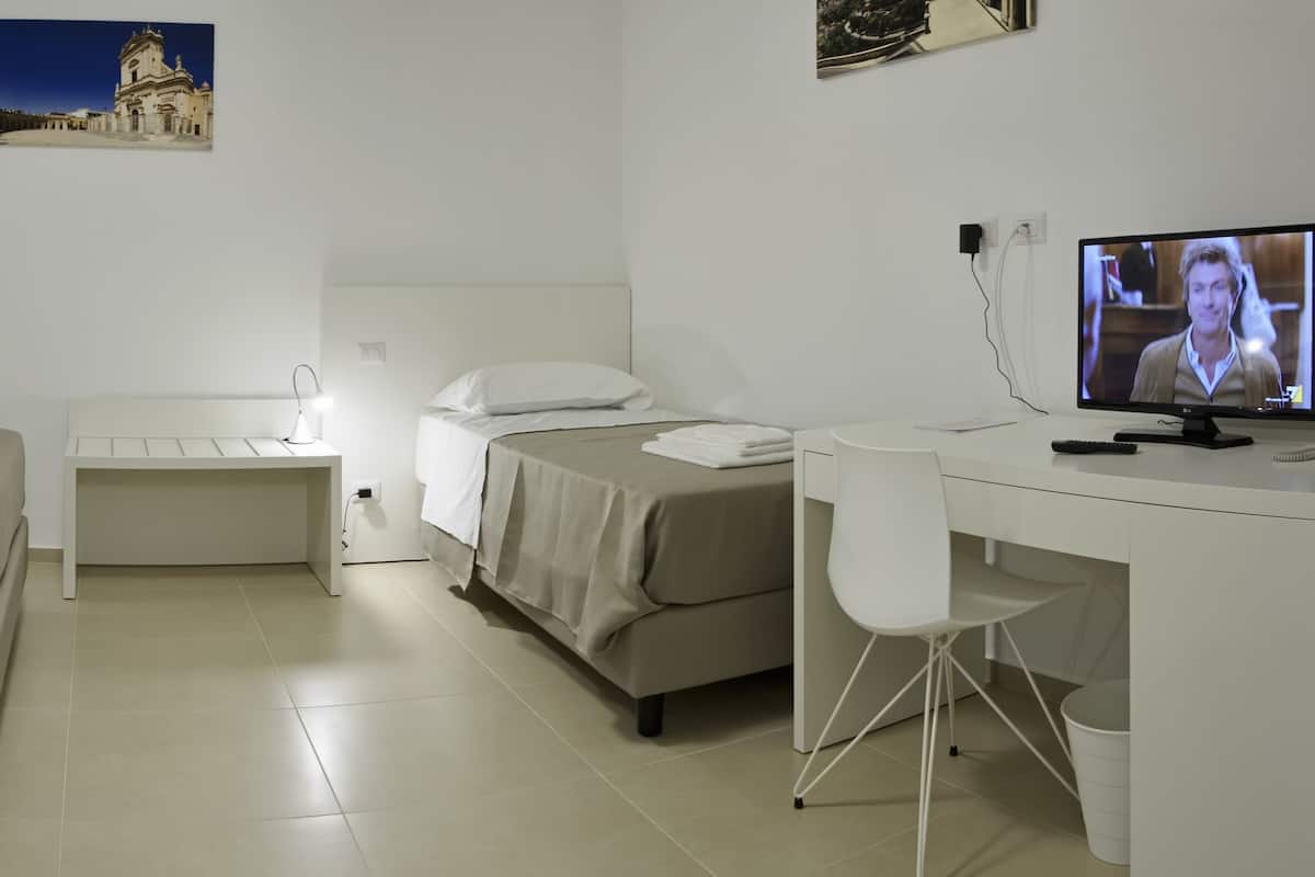 Una habitación de hotel con dos camas, un escritorio, un televisor y una silla pequeña.