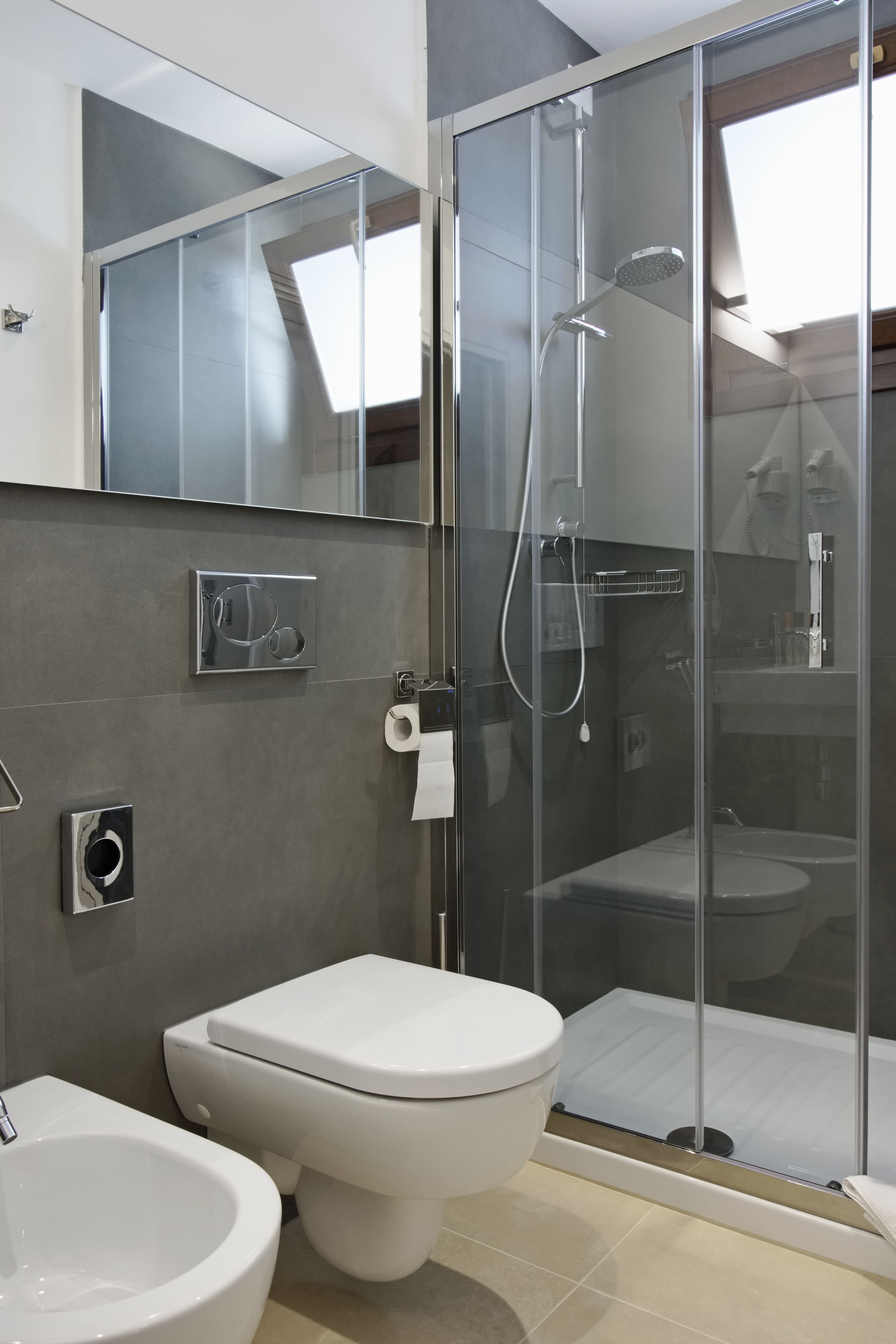 A modern bathroom with a glass-enclosed shower, a toilet, and a bidet.