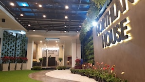 Une entrée d’hôtel moderne, avec une enseigne indiquant « Northland House », un plafond en verre et un chemin menant à l’entrée.