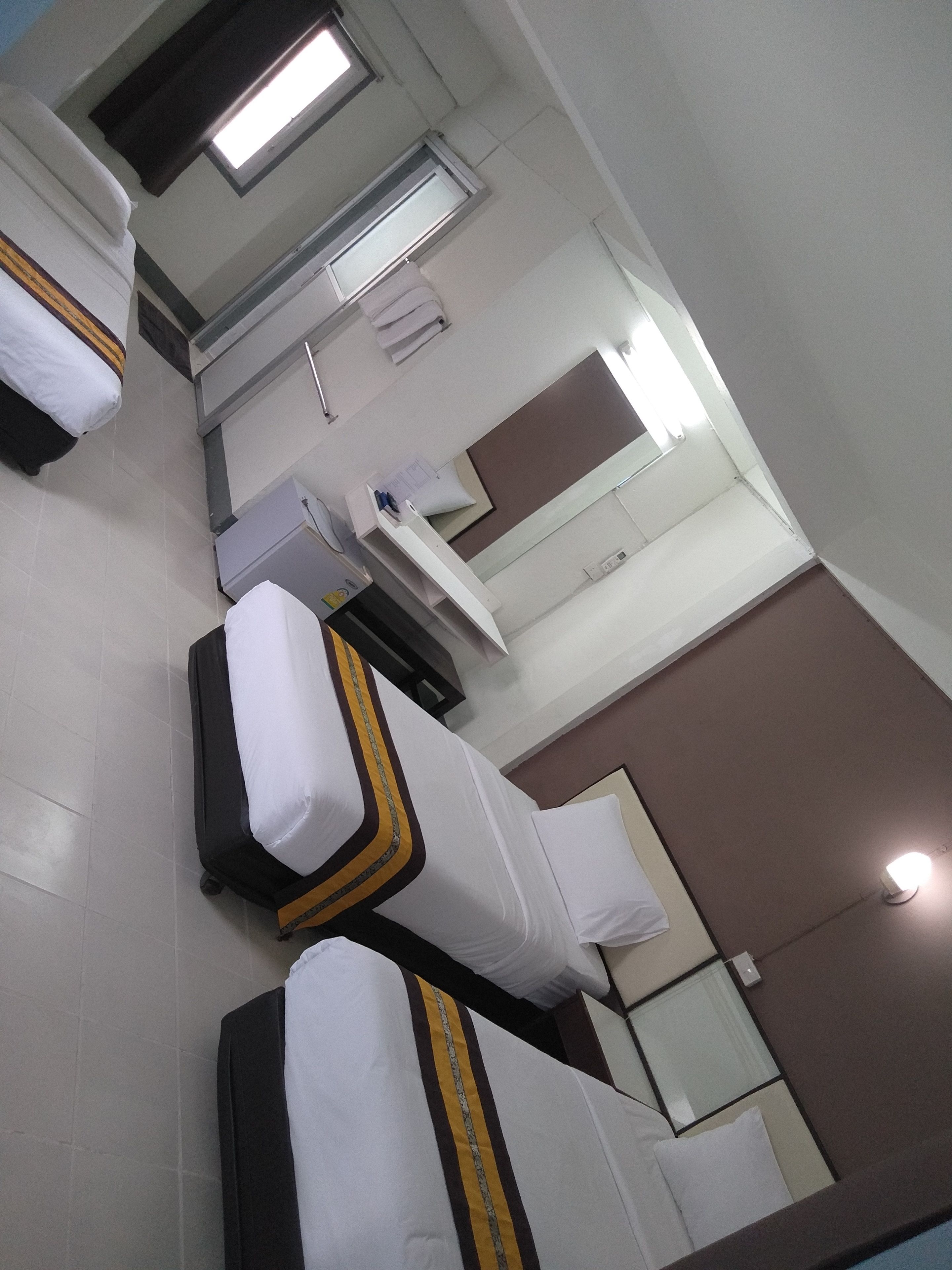 A hotel room with two beds, a bathroom, and a window.