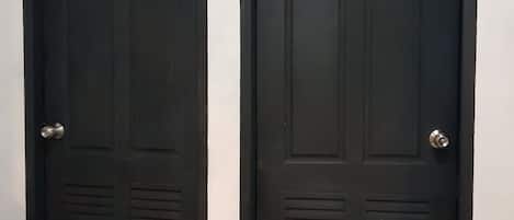 Two black doors with a weather vane on top, a metal handle, and a keyhole.