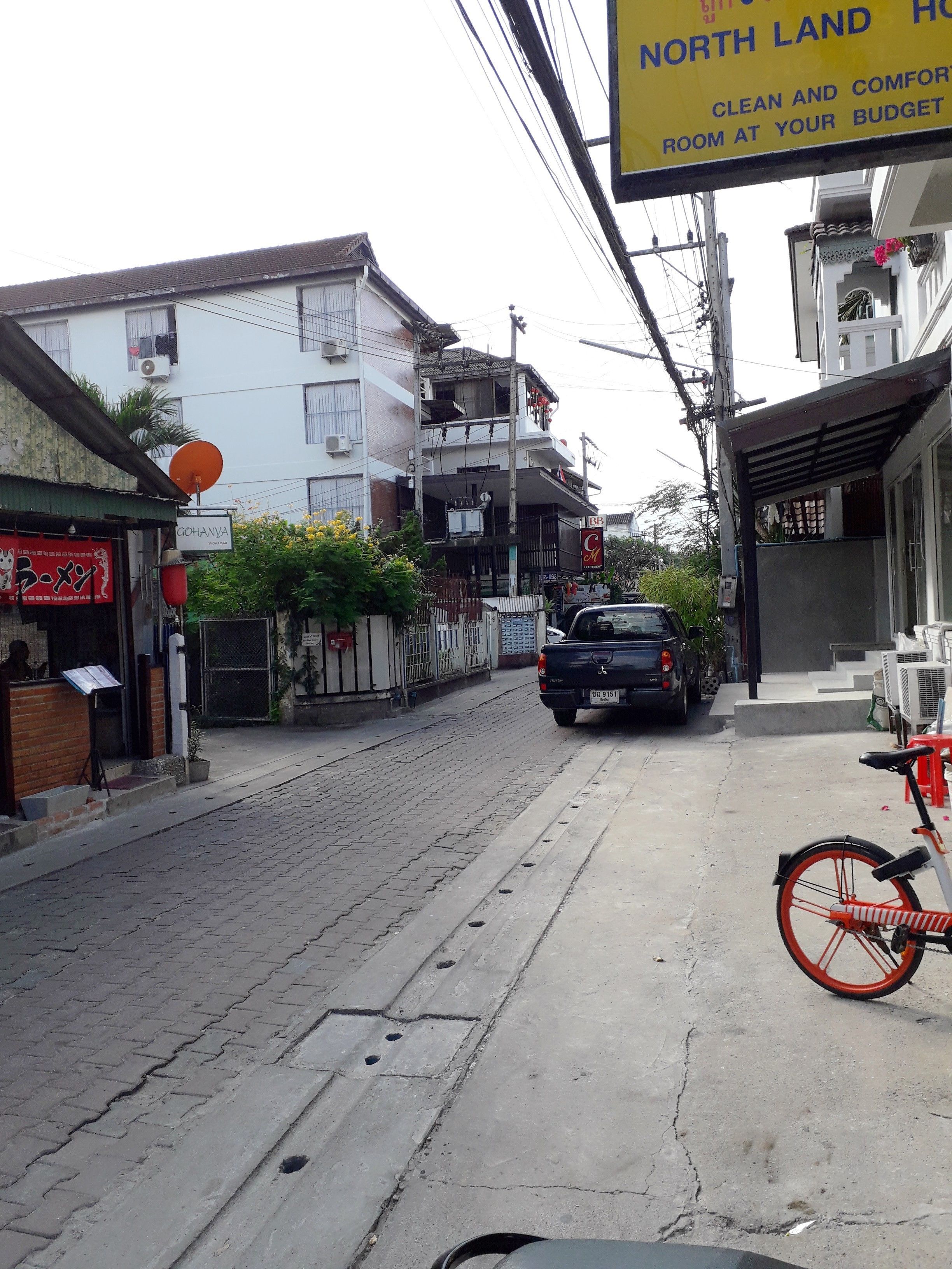 Une vue de rue avec une enseigne indiquant l’hôtel North Land, une voiture garée et un vélo.