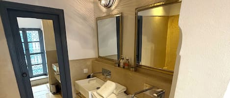 A bathroom with two sinks, a mirror, and a trash bin.