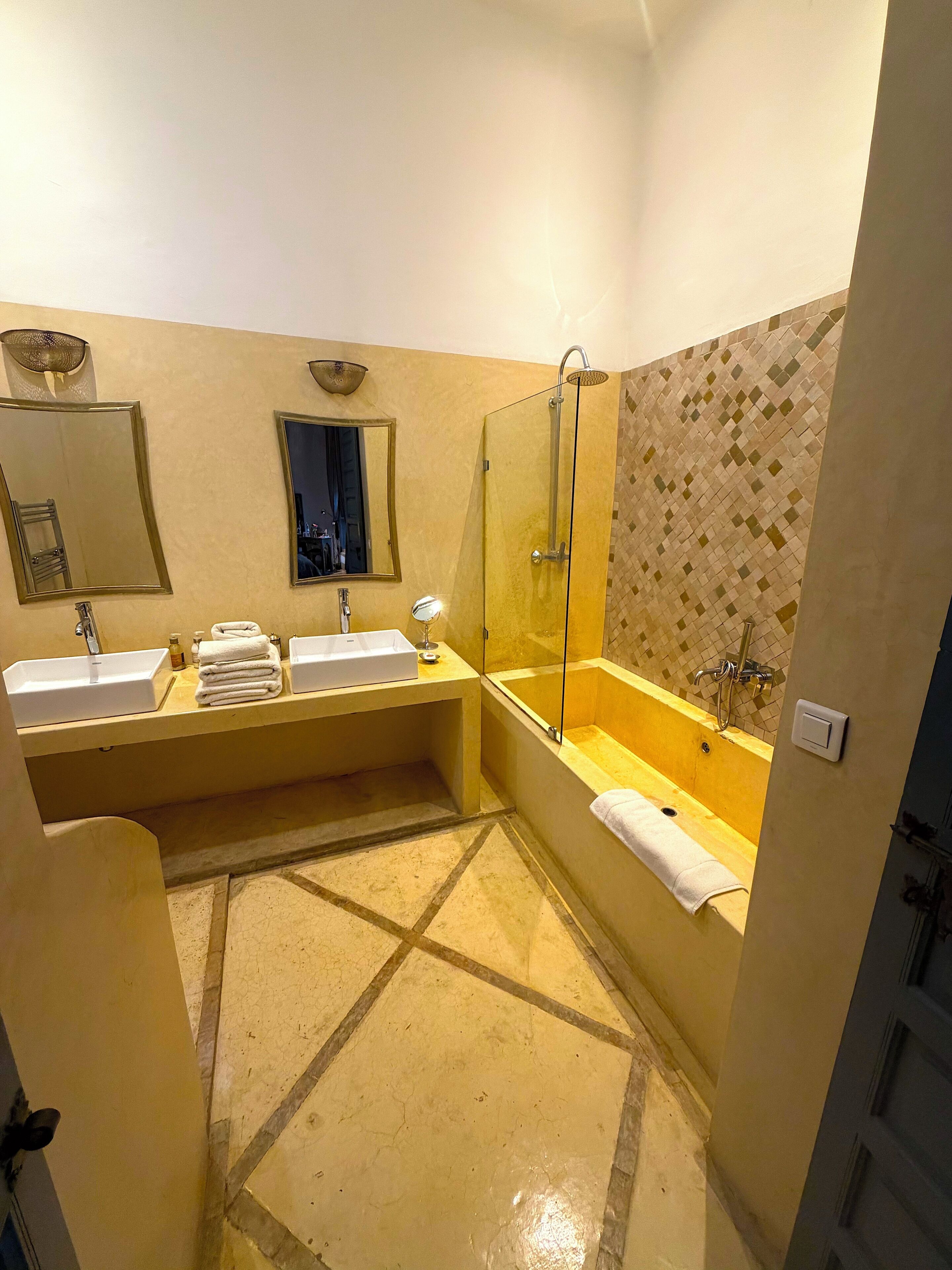 A bathroom with two sinks, a bathtub, a shower, and a tiled floor.