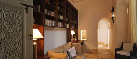 A cozy living room with a sofa, armchairs, a bookshelf, and a decorative door.