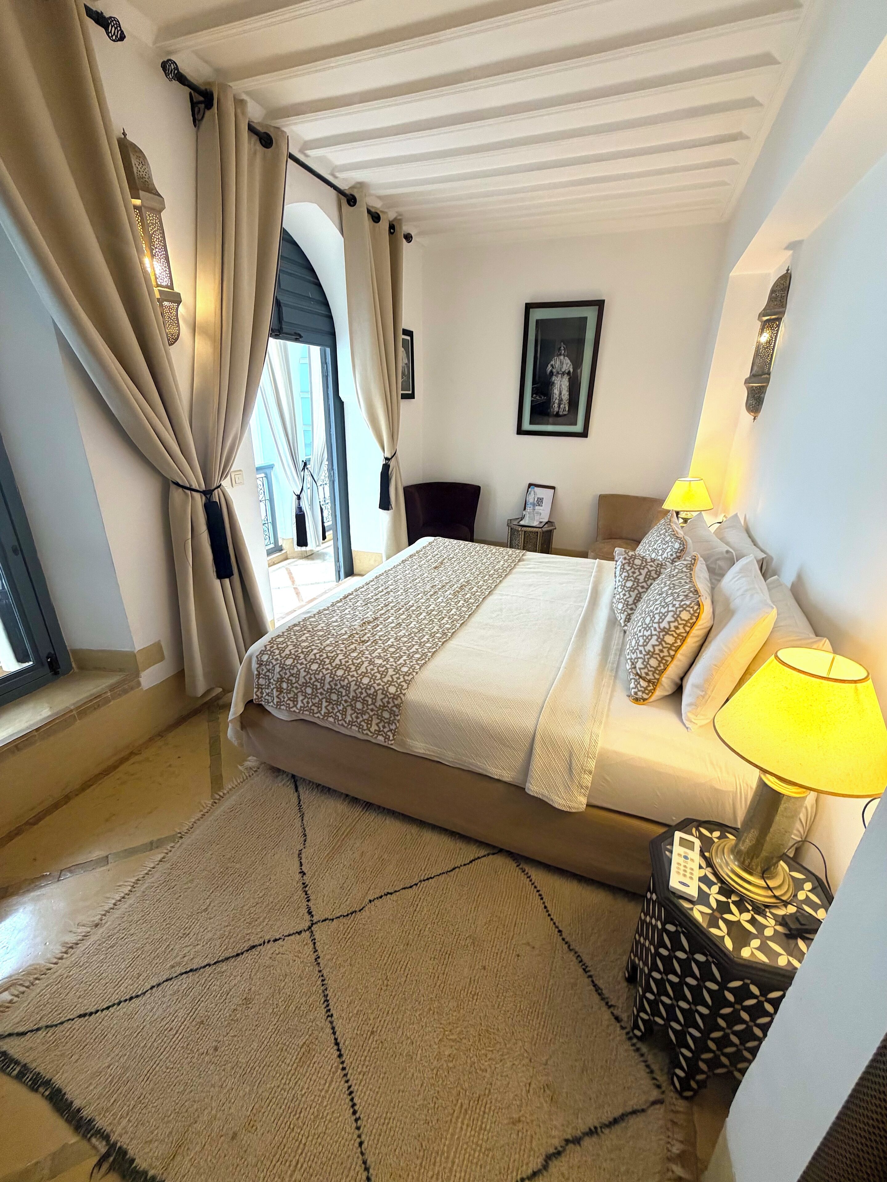 A bedroom with a bed, bedside lamps, a rug, and a nightstand.