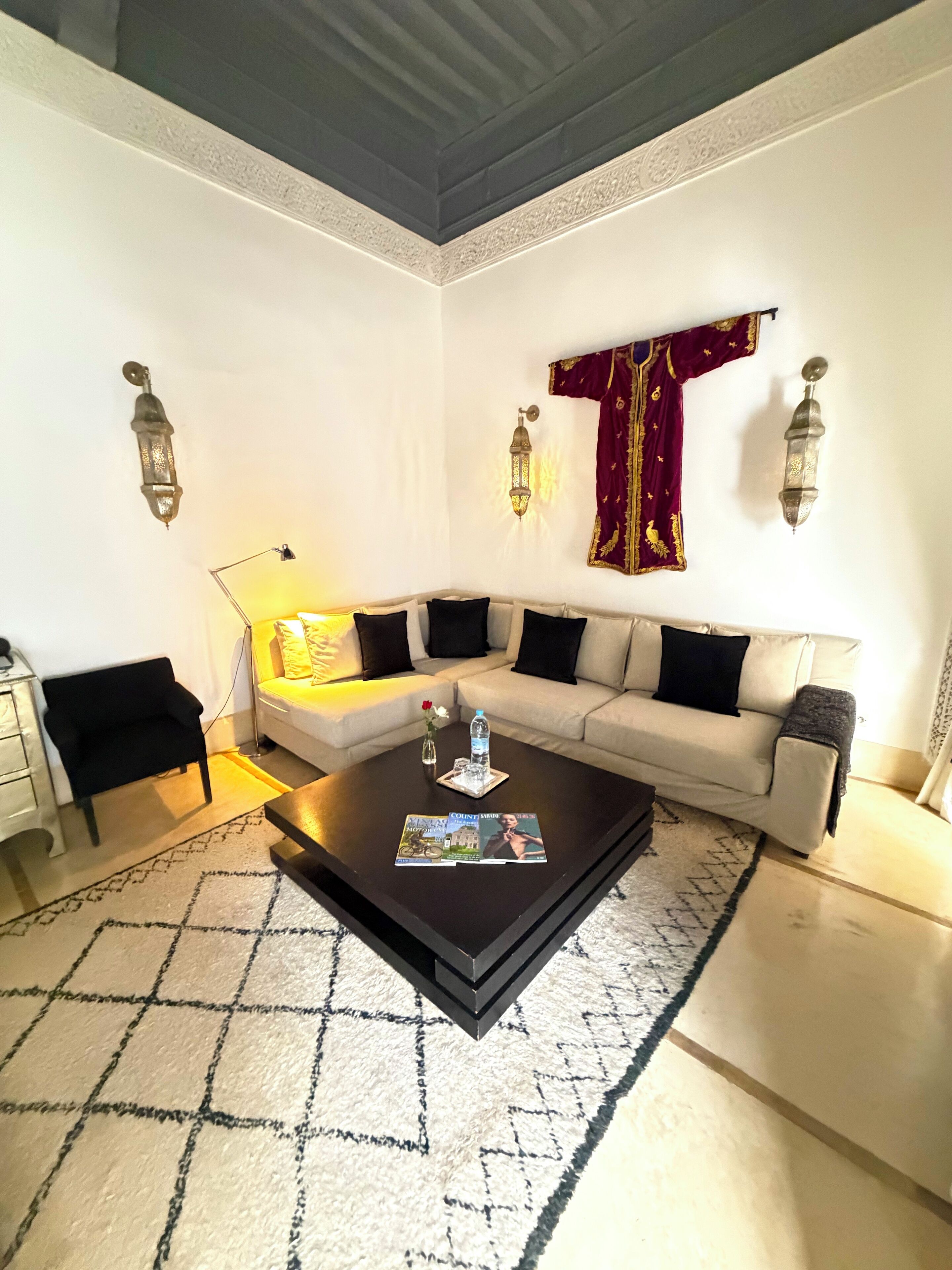 A living room with a sofa, coffee table, and decorative wall sconces.