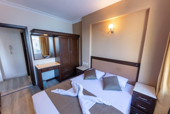 Habitación de hotel con cama, escritorio, armario y una lámpara de pared.