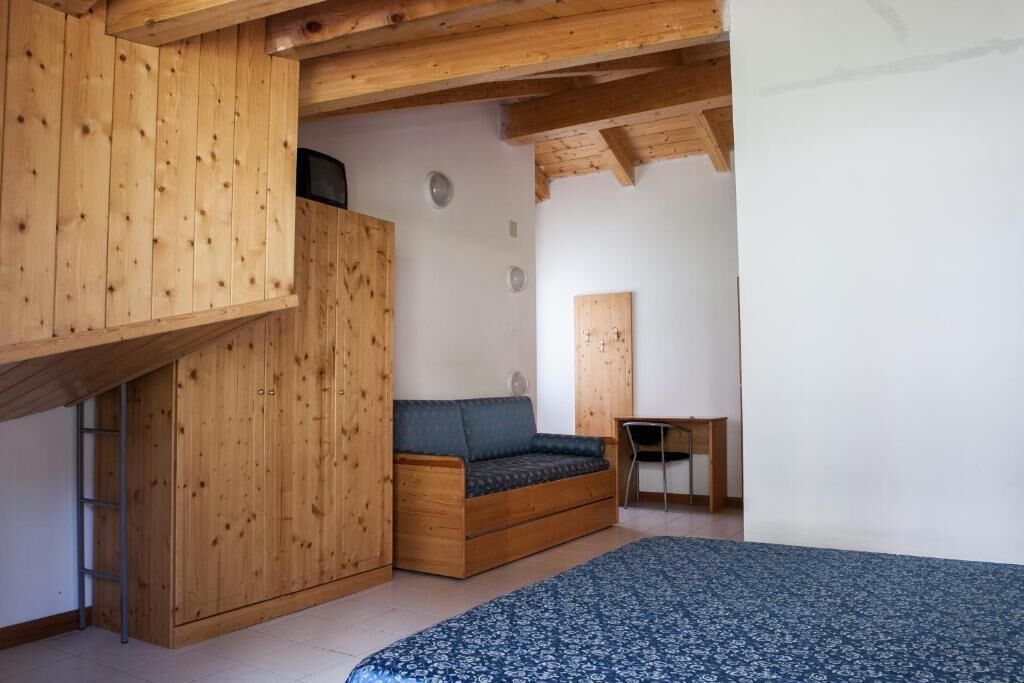 A room with a wooden loft bed, a blue patterned sofa, and a small desk.