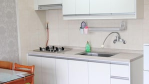 A kitchen with white cabinets, a gas stove, a sink, and a faucet. - Memory Tour (Seogwipo)