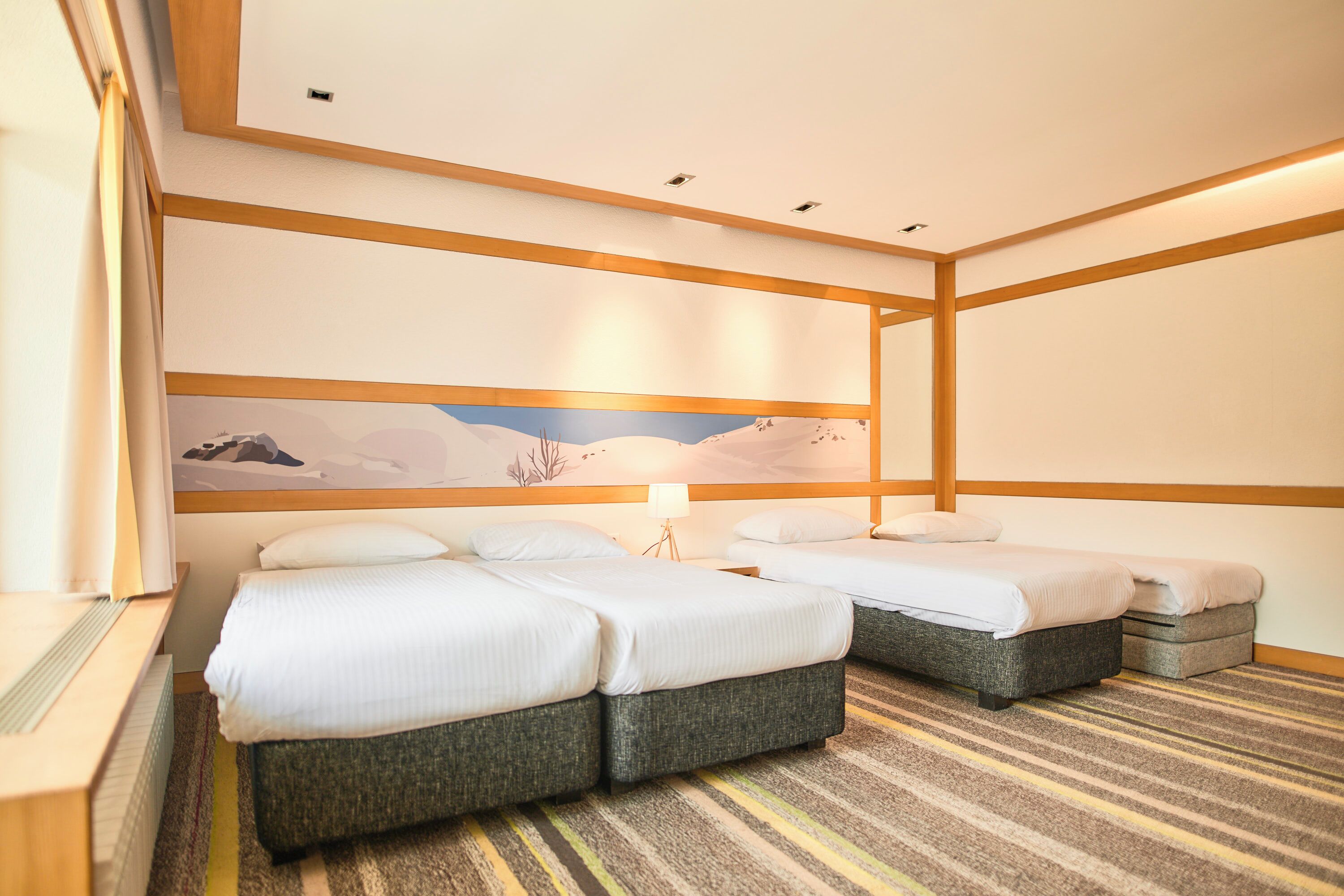 A hotel room with two beds, a large painting on the wall, and a striped carpet.