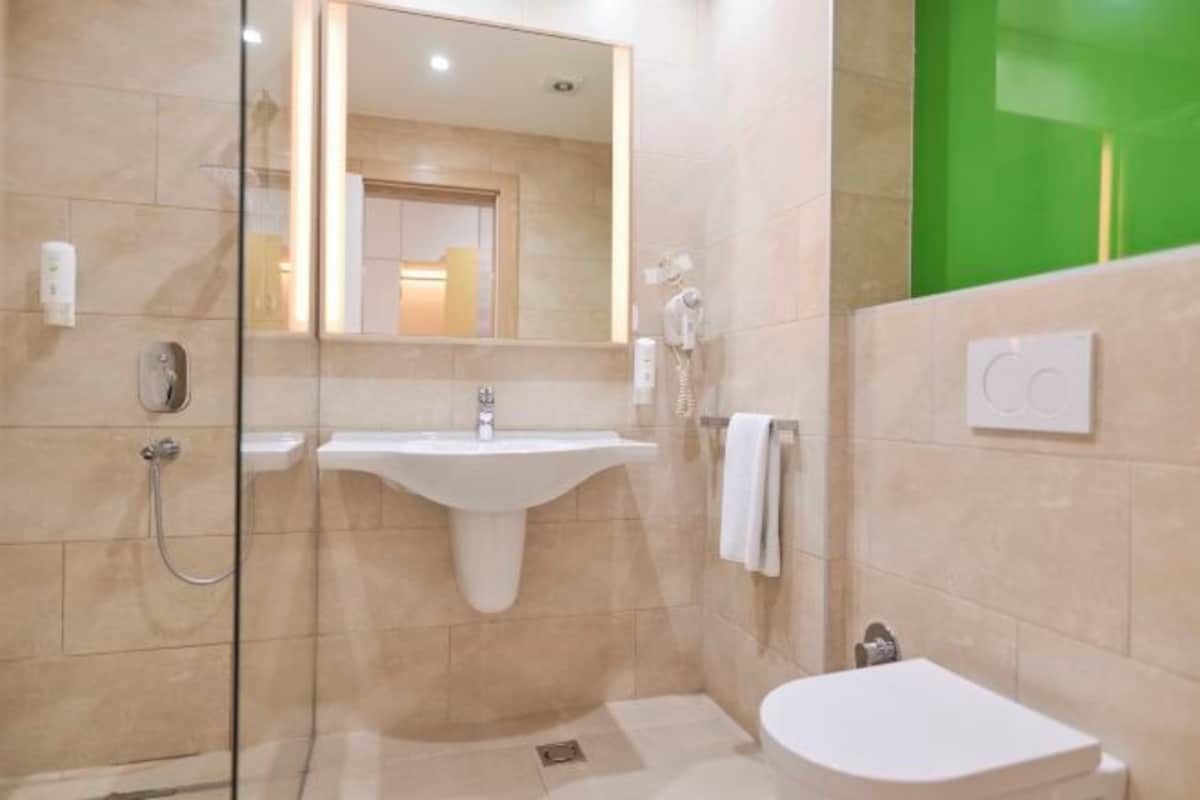 Um banheiro moderno com chuveiro envidraçado, pia de pedestal e vaso sanitário.