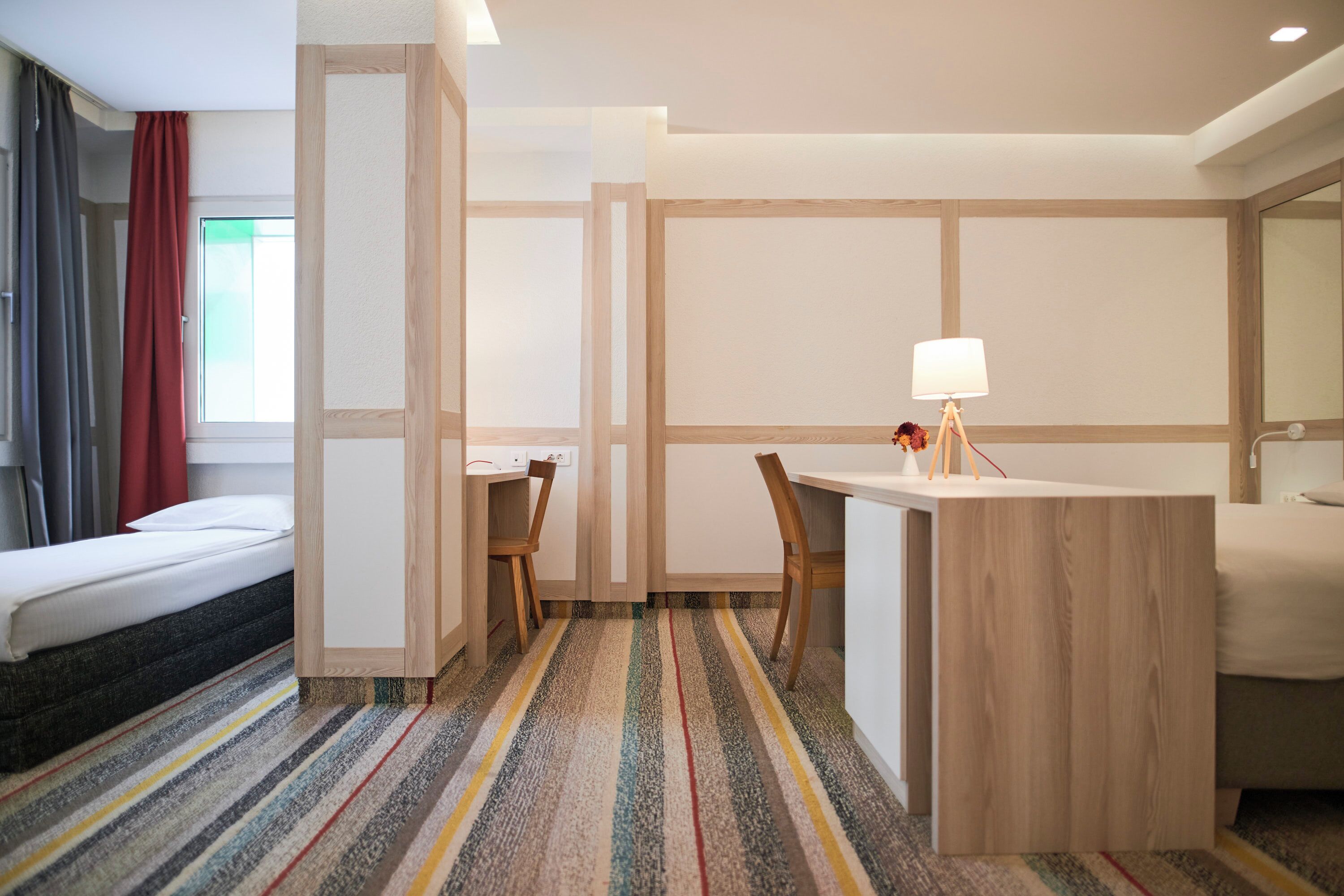 Una habitación de hotel con cama, escritorio, silla y lámpara.