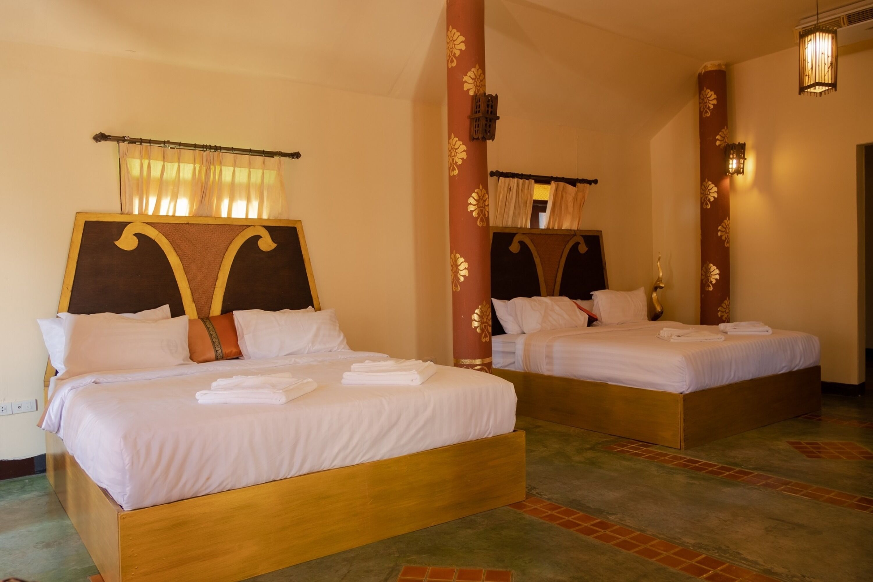 Une chambre d’hôtel avec deux lits en bois, chacun étant équipé de draps et d’oreillers blancs.