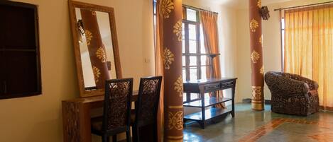 A room with a dining table, chairs, a sofa, and a large mirror.