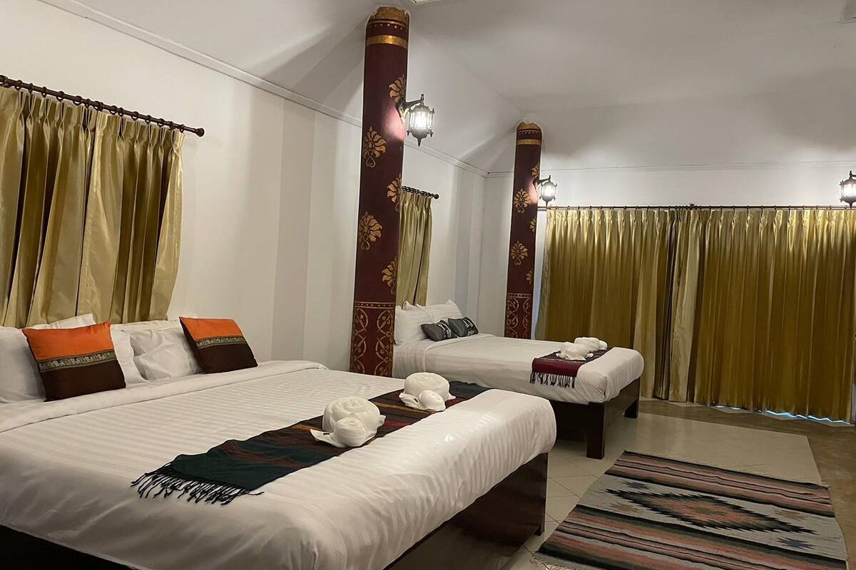 A hotel room with two beds, a large window with curtains, and a patterned rug.
