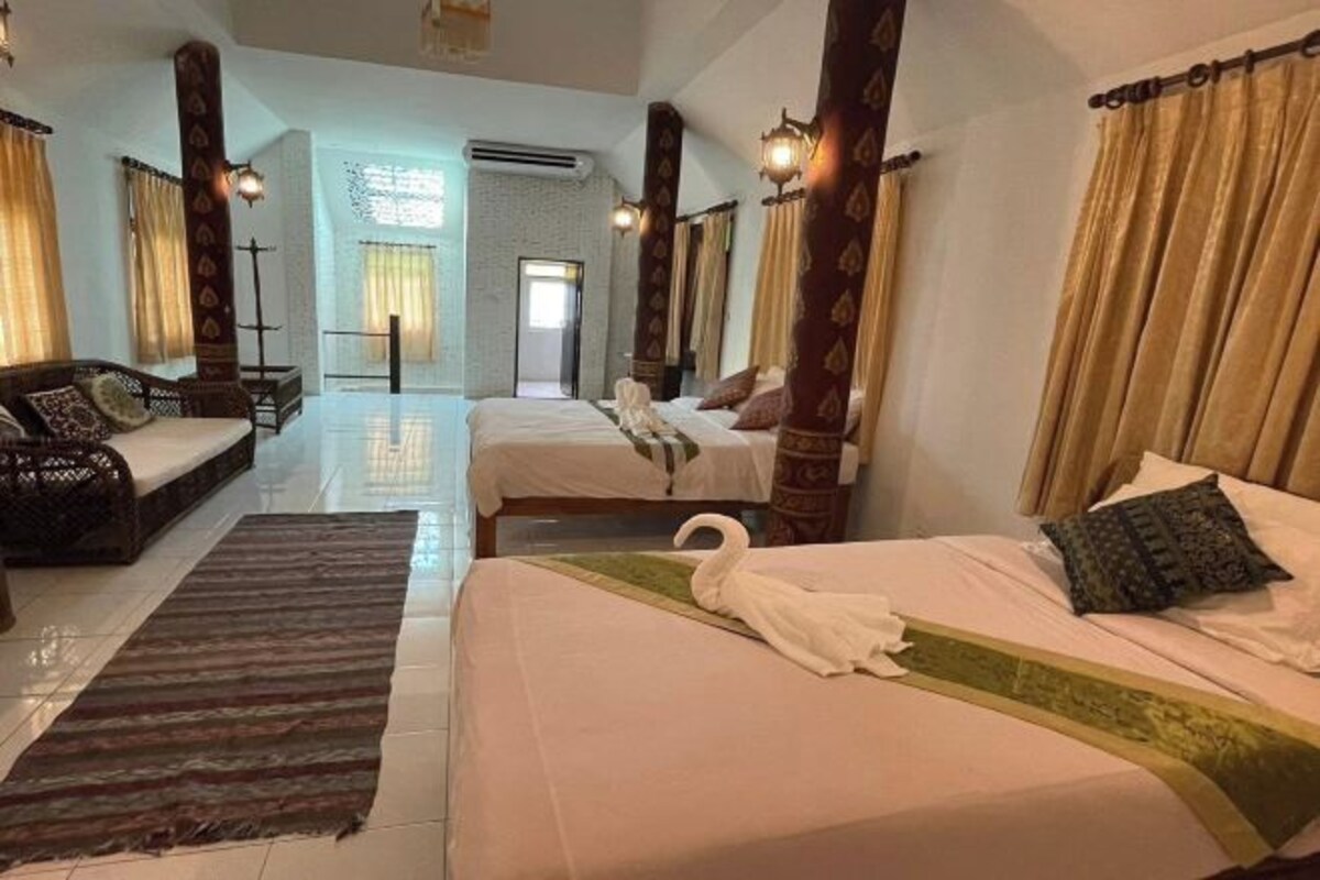 A hotel room with two beds, a sofa, and a large window.