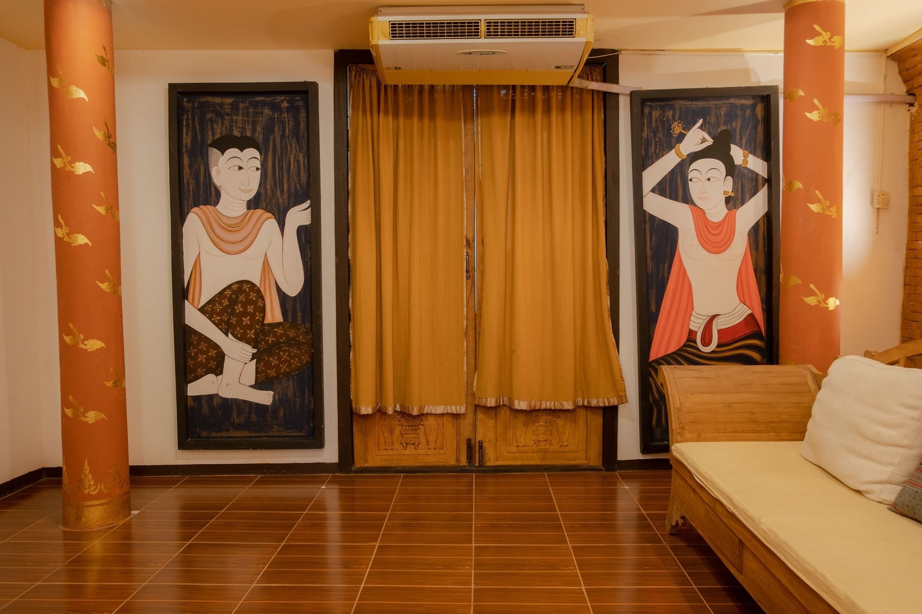 Een kamer met een houten bed, twee schilderijen aan de muur, een raam met gele gordijnen en een airconditioner boven het raam.