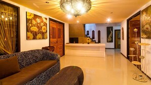A modern lobby with a sofa, a reception desk, and a decorative ceiling light. - Baan Tawai Lanna Resort (Hang Dong)