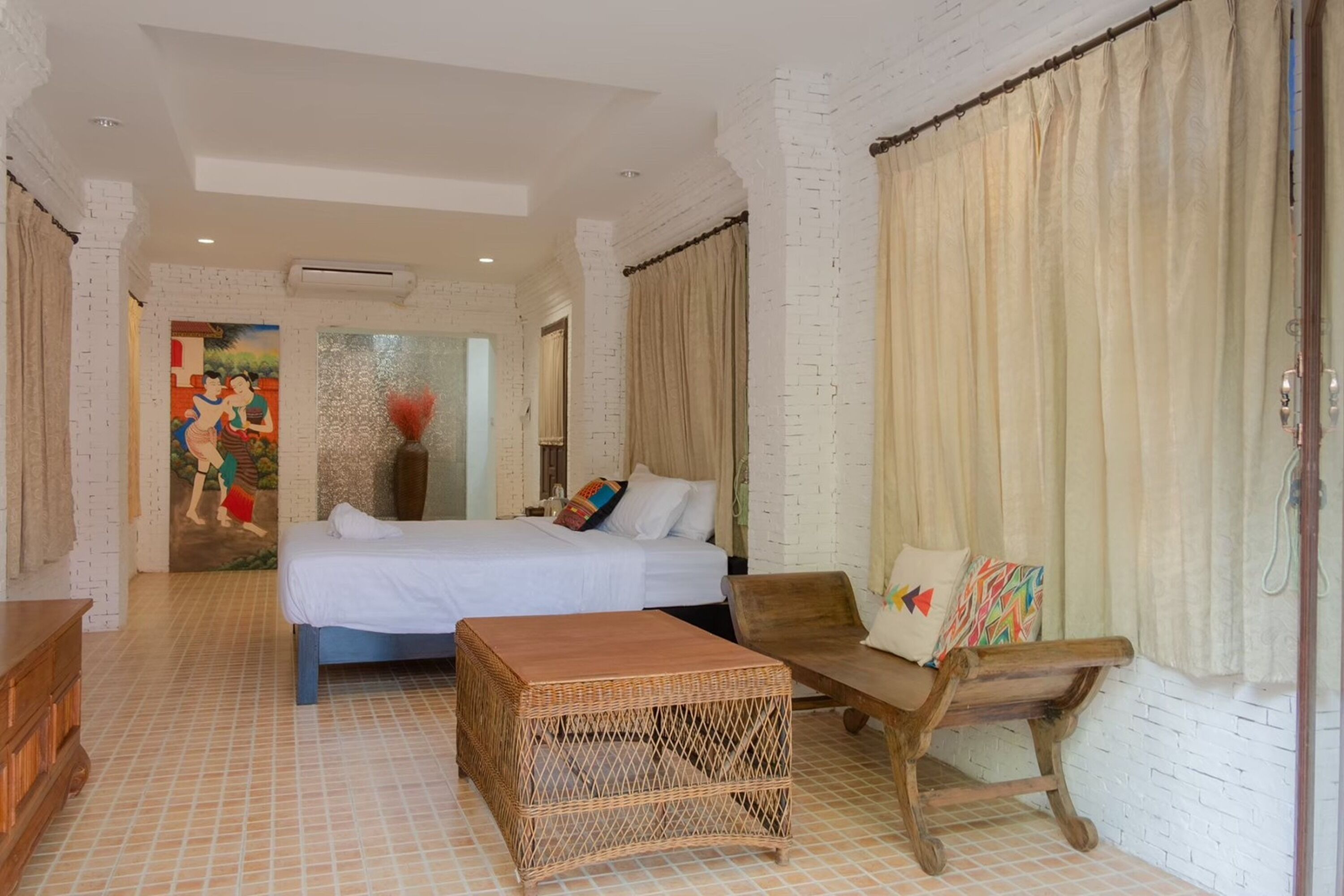 Una habitación con una cama, una silla de madera, una mesita y un cuadro en la pared.