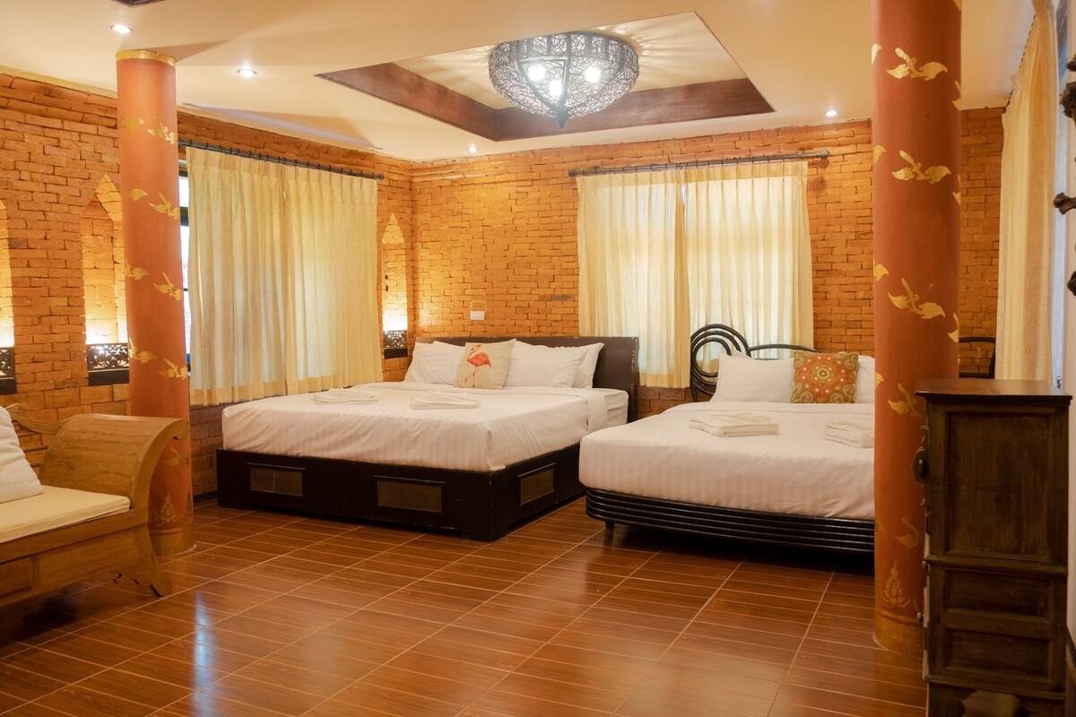 A hotel room with two beds, a wooden chair, a wardrobe, and brick walls.