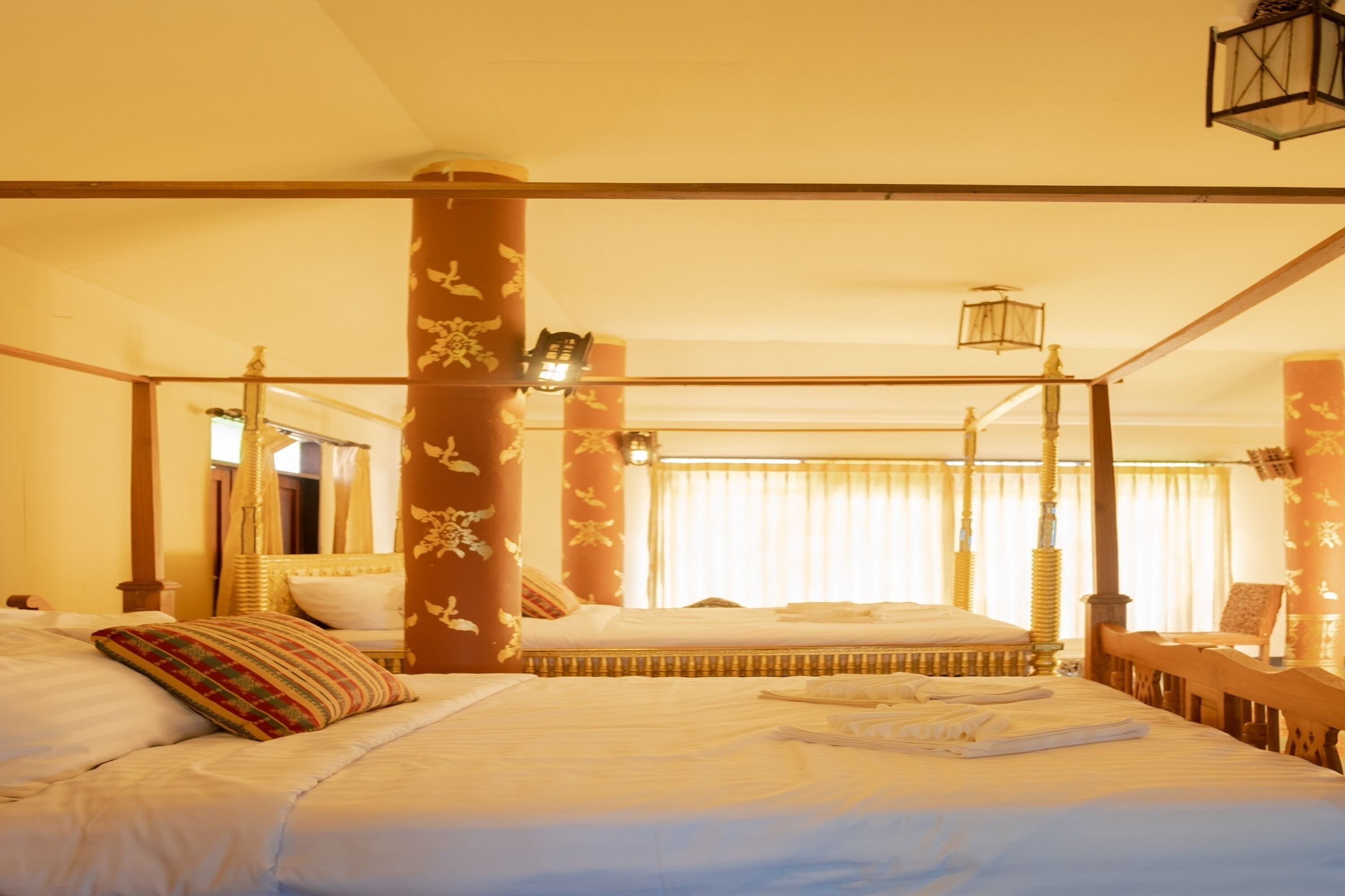 A four-poster bed with a canopy, a bedside table, and a chair.