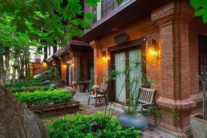 A traditional brick building with a courtyard. There are benches and potted plants. - Baan Tawai Lanna Resort (Hang Dong)