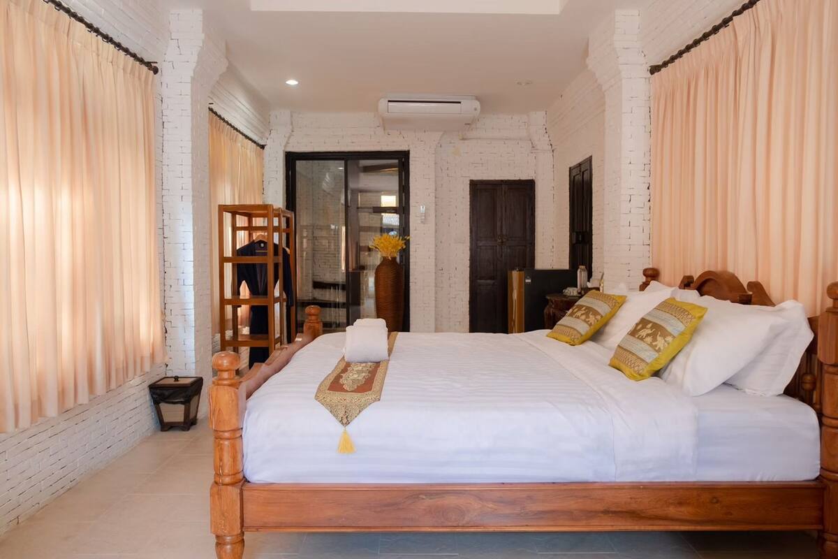 A neatly made bed with a wooden frame, white bedding, and decorative pillows.