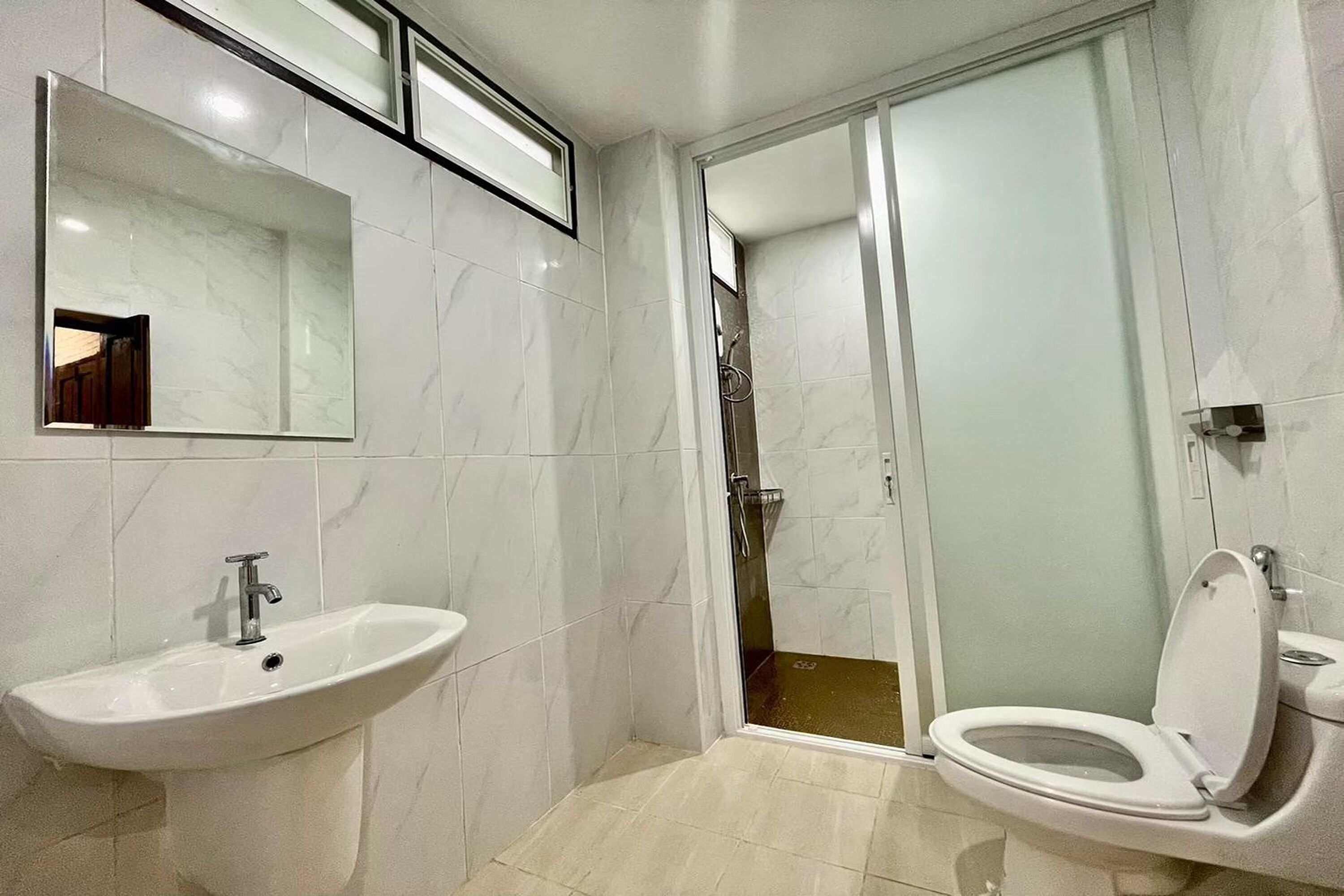 A modern bathroom with a sink, toilet, and glass shower enclosure.