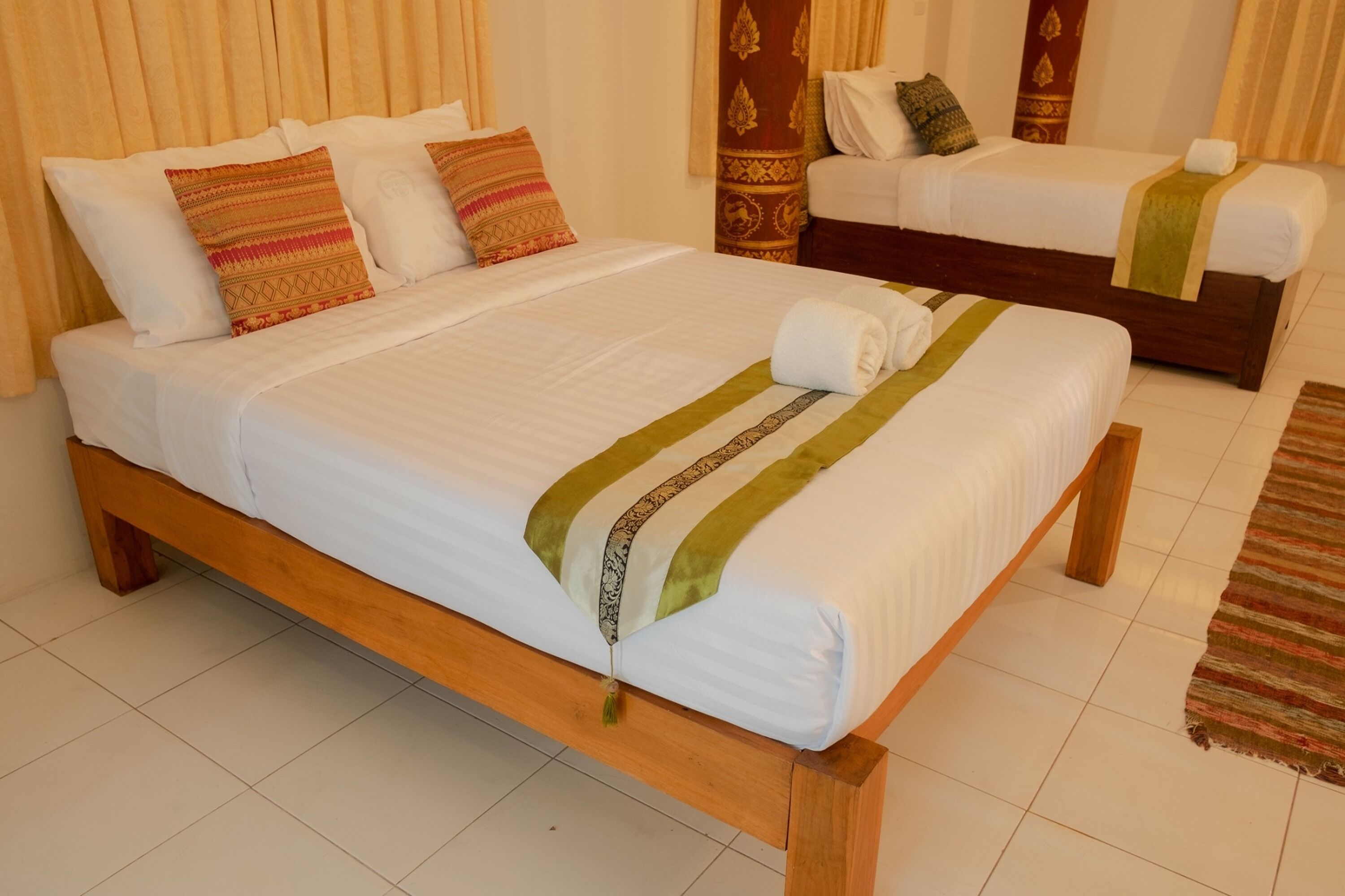 A double bed with a wooden frame, white bedding, and decorative pillows.
