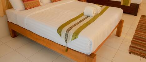 A double bed with a wooden frame, white bedding, and decorative pillows.