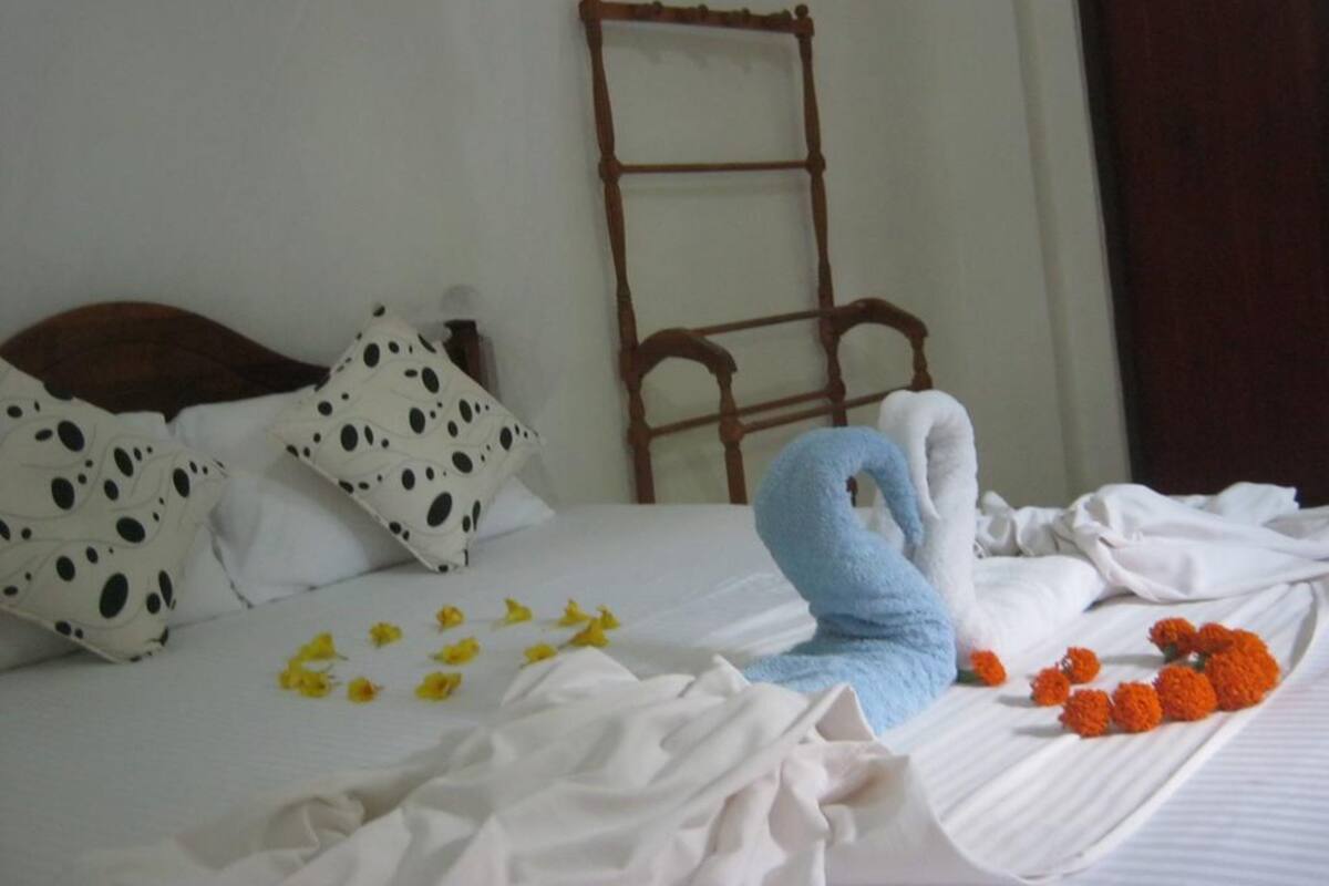 A bed with a white sheet, a blue towel, and orange flowers.