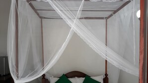 A bed with a canopy, green pillows, and a folded white towel. - Arcade Beach Hotel (Induruwa)